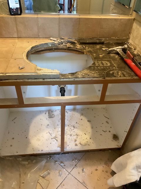 Bathroom vanity demolition: Damaged countertop, exposed cabinet frame, hole for sink.