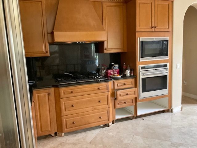 Kitchen with wooden cabinets, black countertops, and stainless steel appliances.