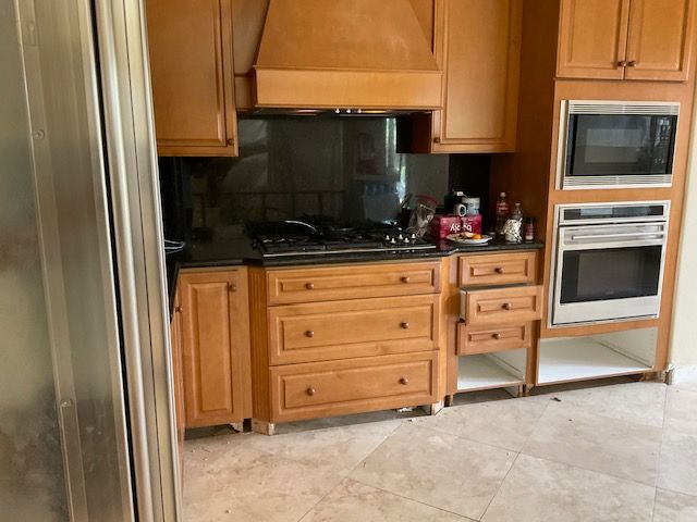 Kitchen with wood cabinets, black countertops, stove, microwave, oven, and refrigerator.