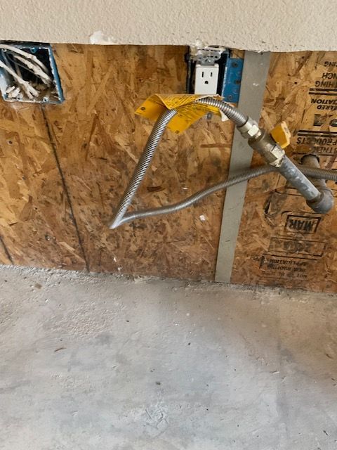 Gas line with flexible hose, and electrical outlet in unfinished wall.