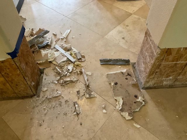 Debris from construction on a tiled floor, near columns. Beige, tan, and broken white materials.