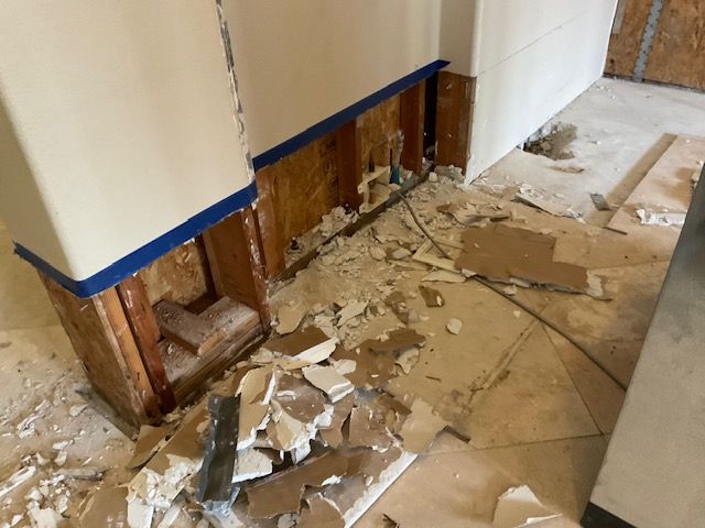 Interior view of exposed wooden framing, rubble, and partially removed wall sections, likely under renovation.