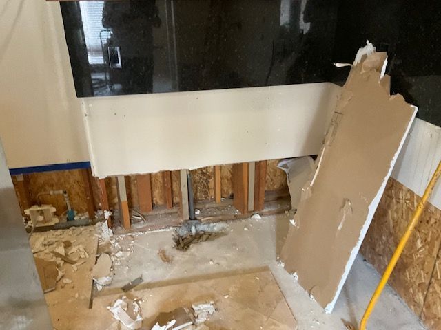 Bathroom under renovation; exposed studs, drywall debris on floor and wall.