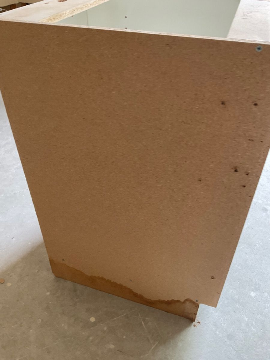Beige cabinet side with water damage at the bottom.