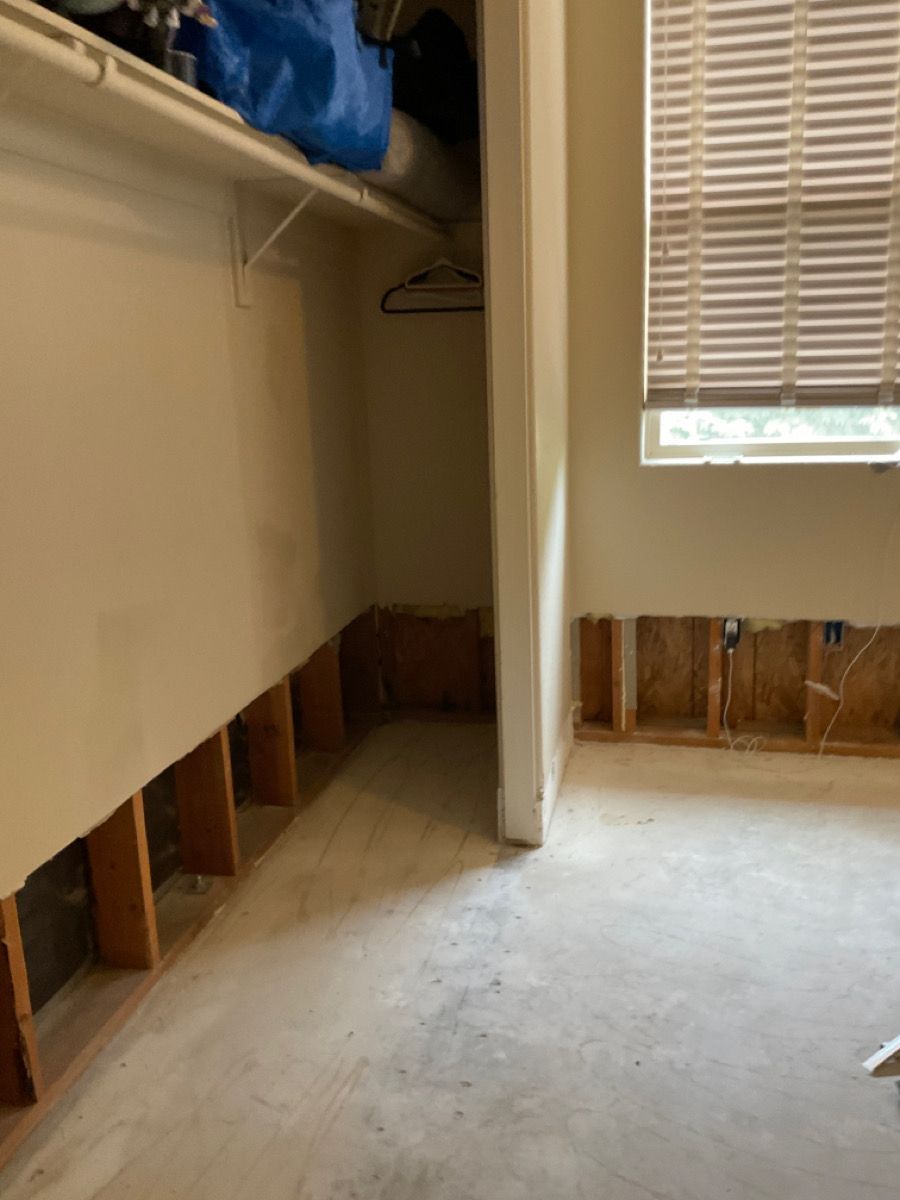 Room with exposed wall studs, likely due to flooding. A closet and window are visible.