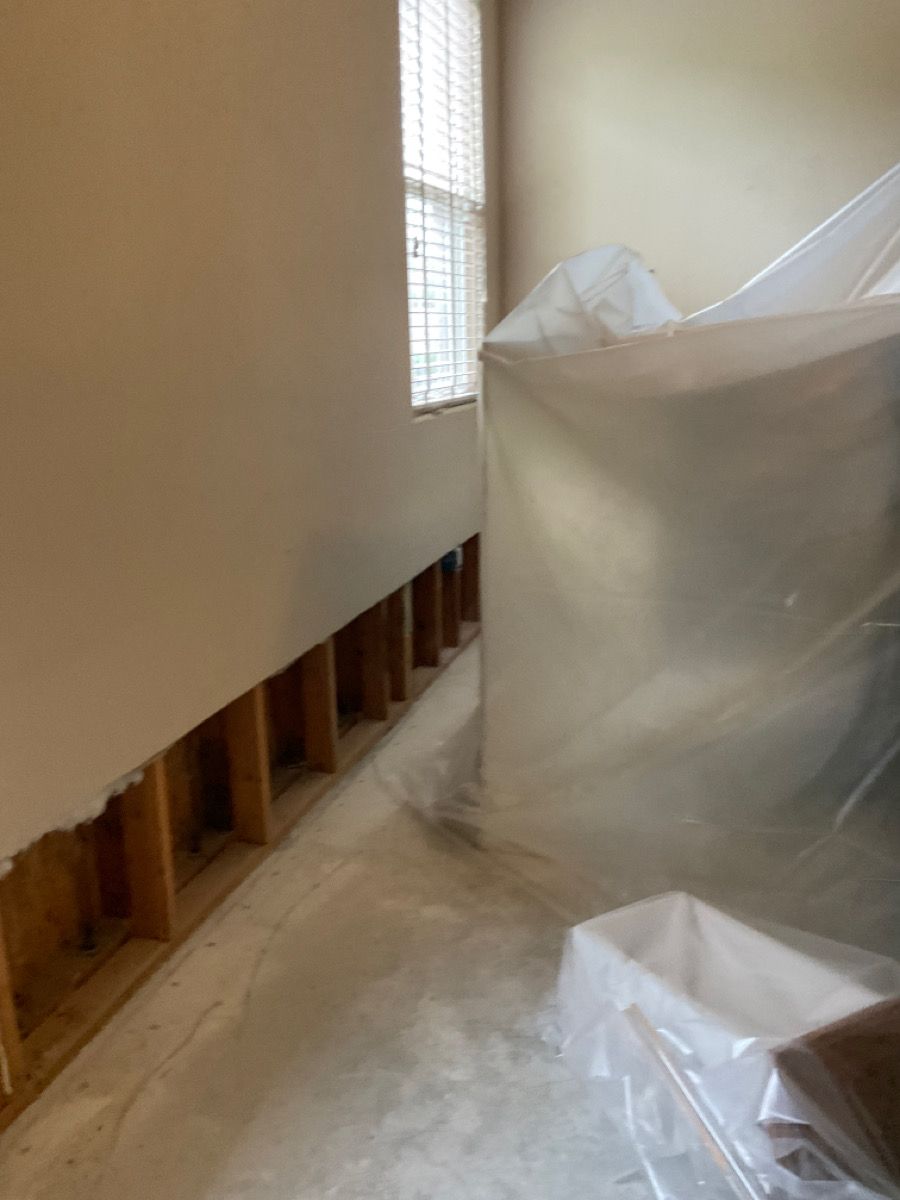 Wall construction with exposed studs, alongside a covered object near a window.
