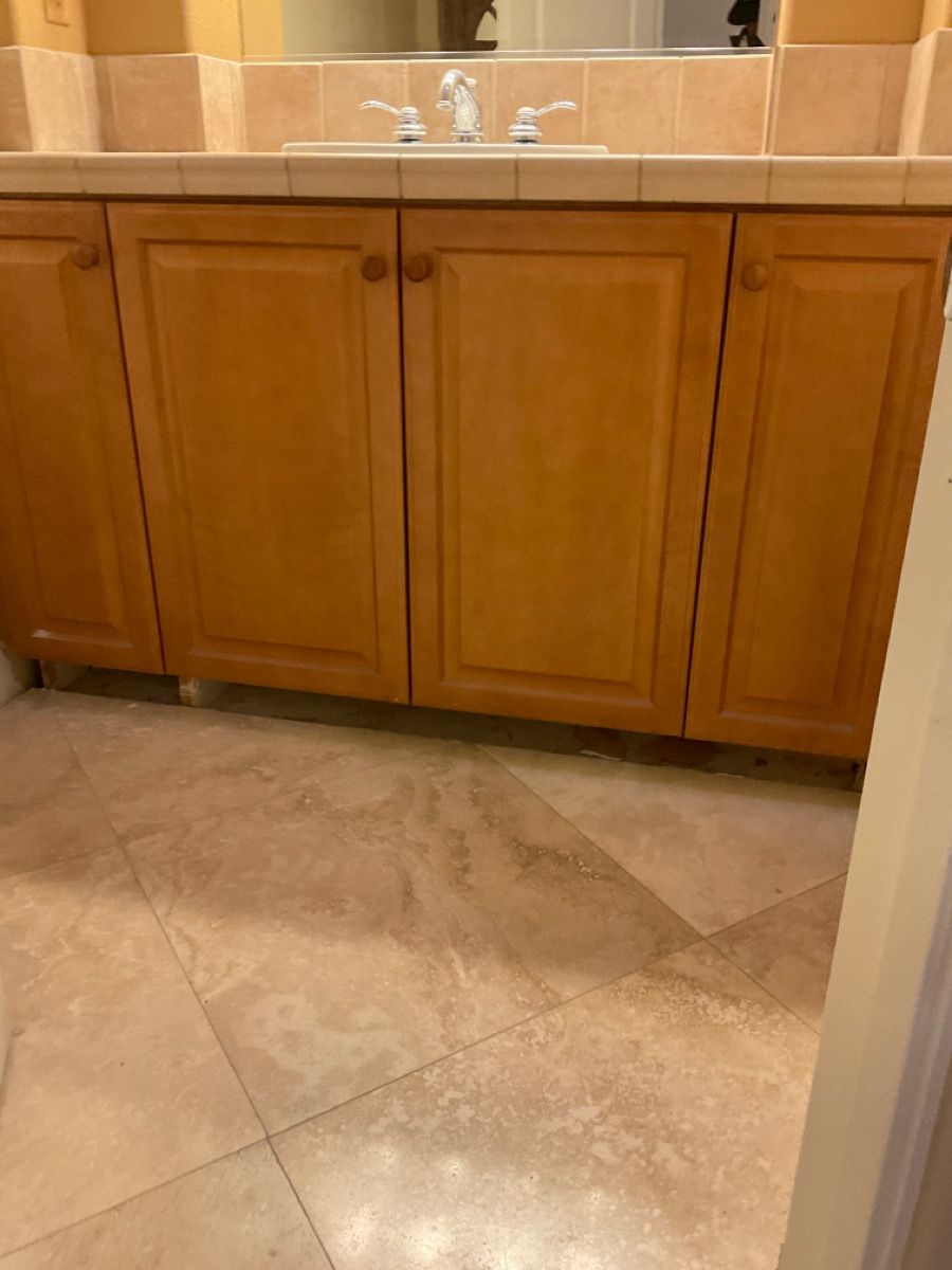 Bathroom vanity with light brown cabinets, beige counter, and beige tile floor.