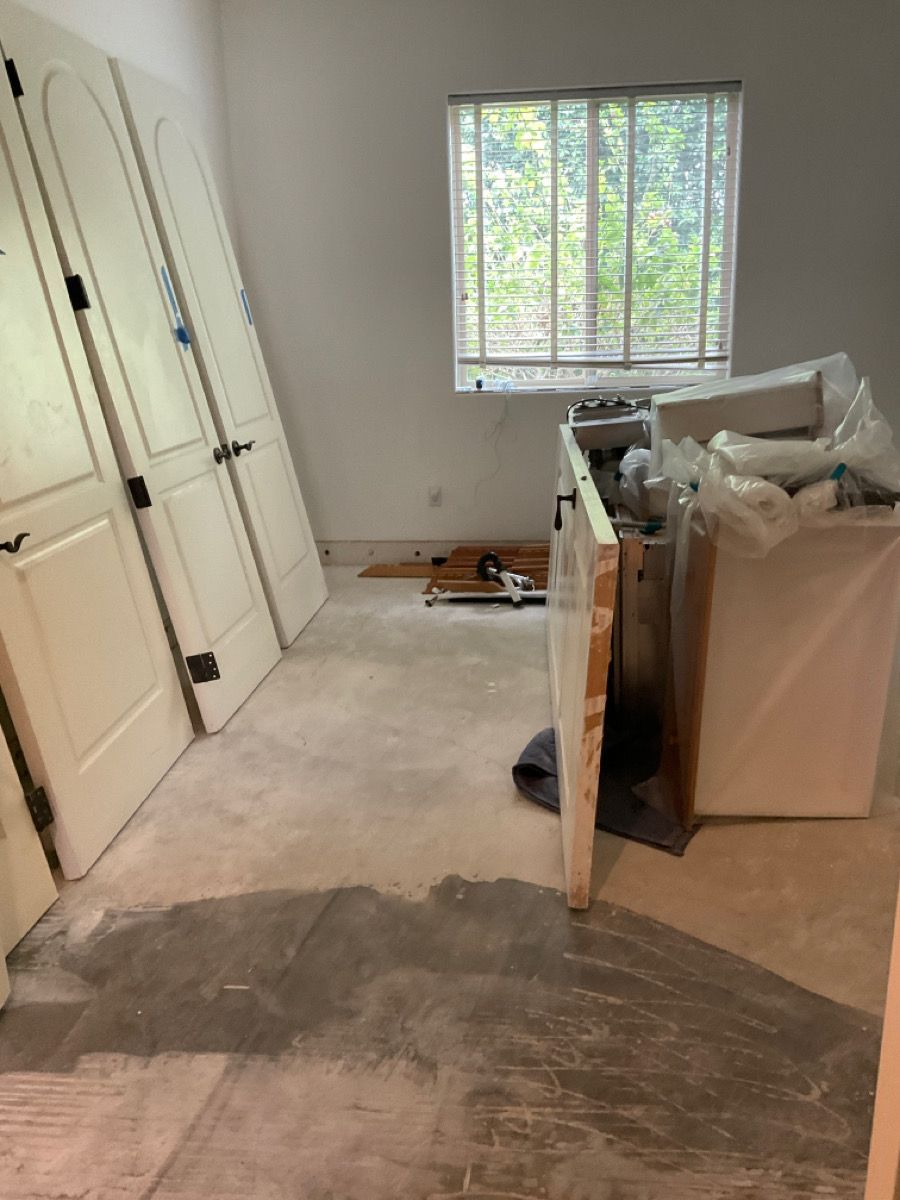 A room with several white doors leaning against a wall, a window, and some construction materials.