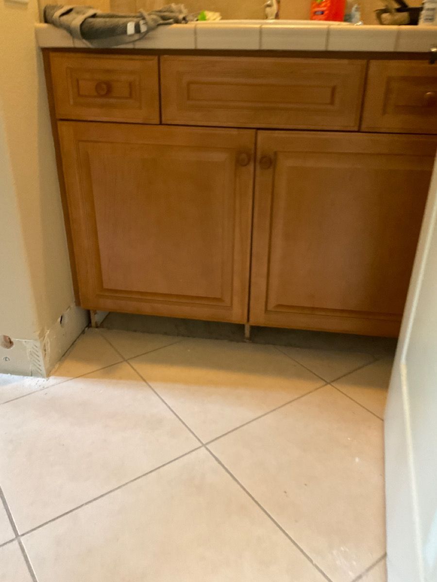 Bathroom vanity with light brown cabinets on a tiled floor.