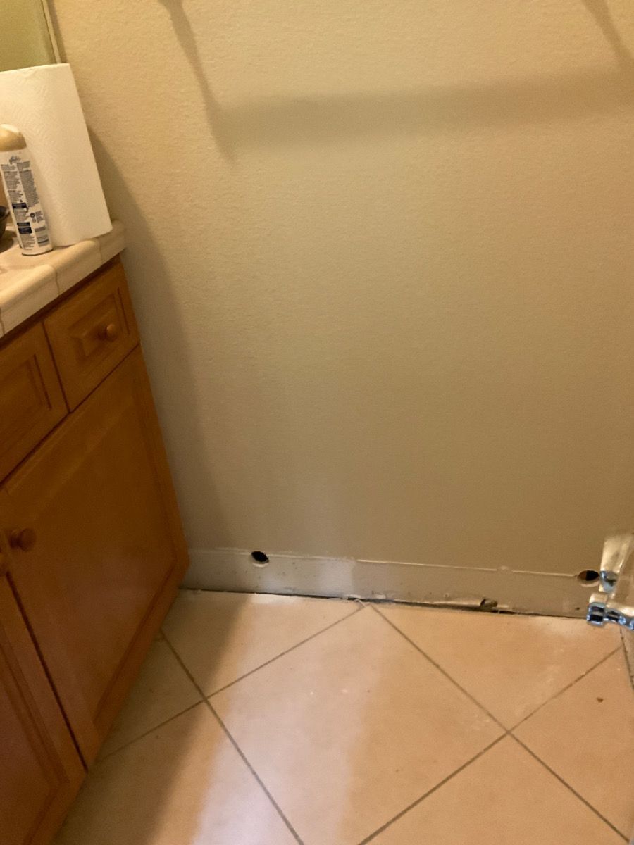 Bathroom corner with vanity, beige walls, and tiled floor.