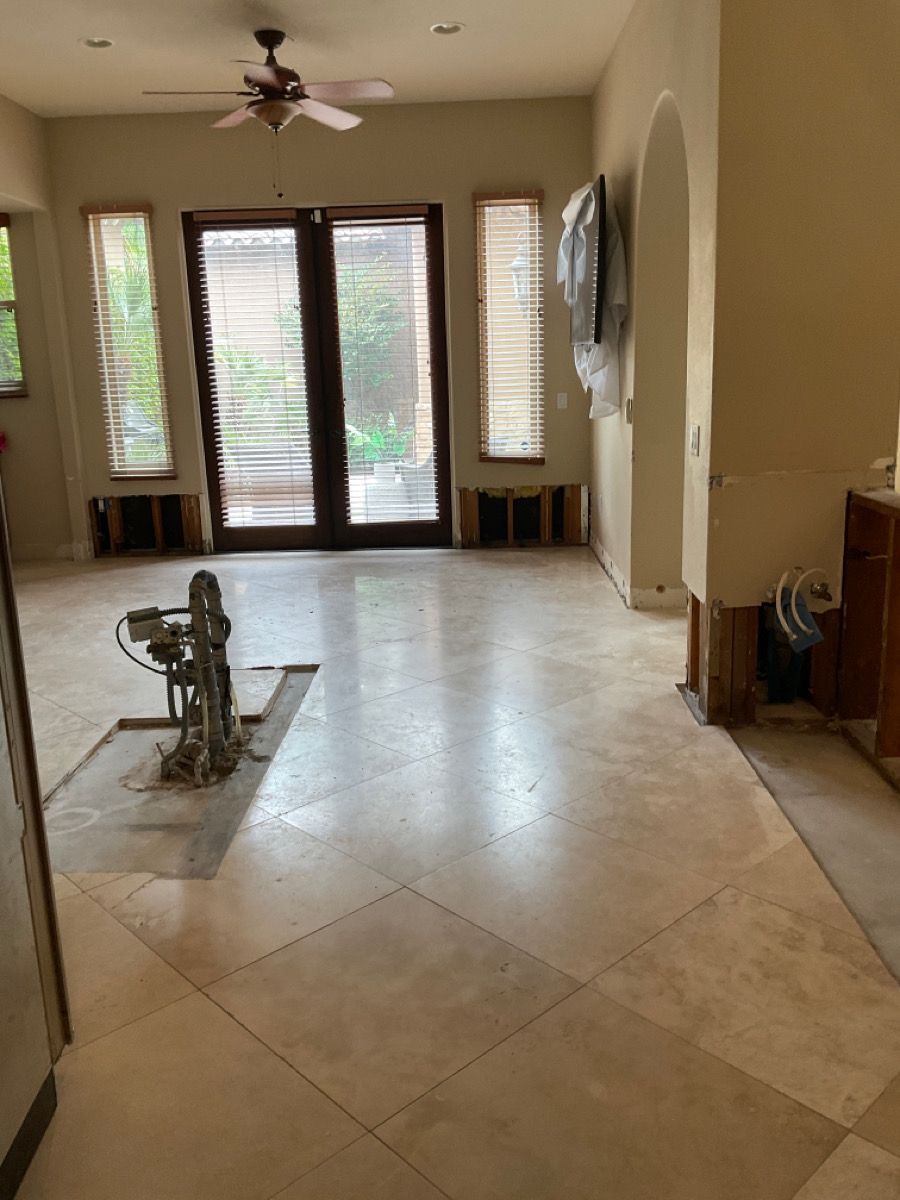A room with light-colored tile flooring, missing baseboards, French doors, and a ceiling fan.