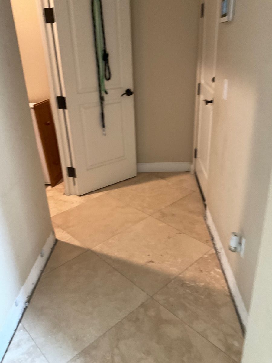 Hallway with beige tile floor and walls, two white doors, one open.