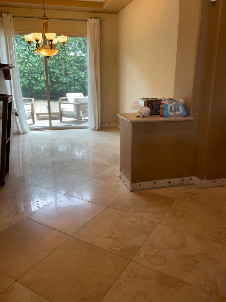 Light-filled dining room with beige tile floor, sliding glass door, chandelier, and small cabinet.