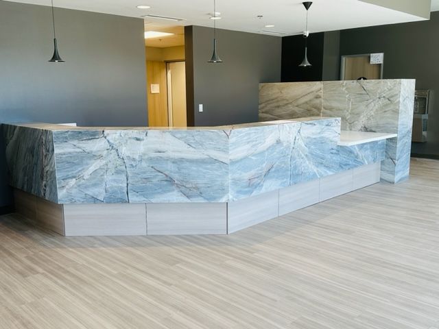 Reception desk with blue marble countertop, beige cabinets, and gray walls.