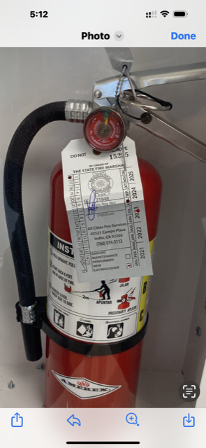 A red fire extinguisher with a tag attached, mounted in a white cabinet.