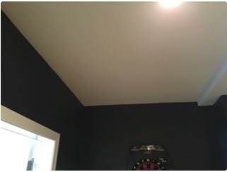 Dark walls, white ceiling. Dartboard on the wall. Corner of a room.