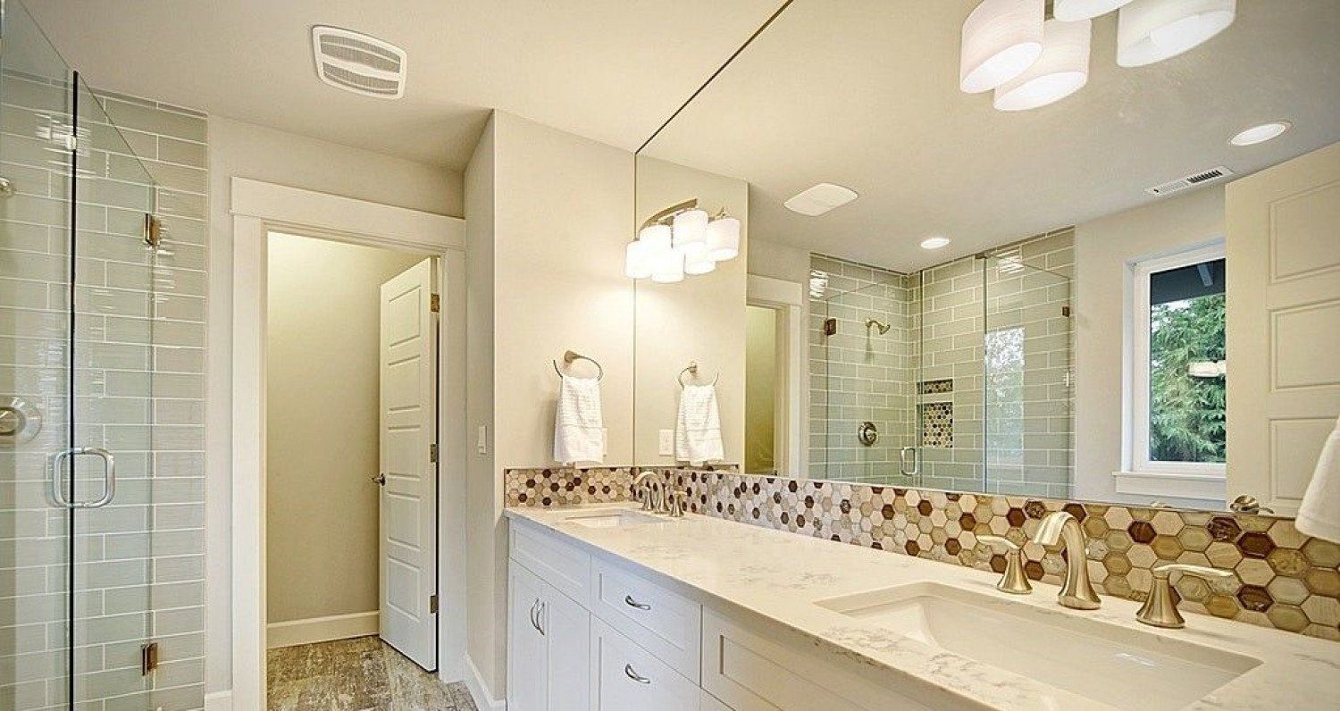 Bathroom with white vanity, long mirror, glass shower, mosaic backsplash, and pendant lights.