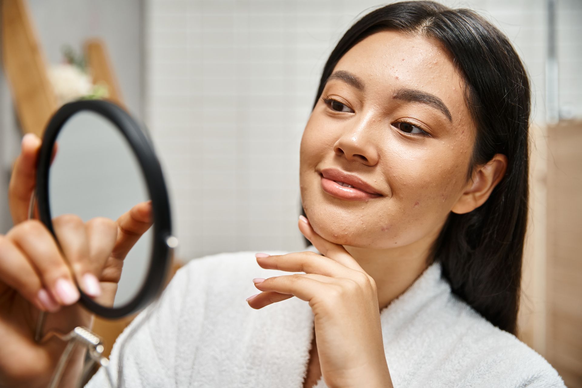 A woman is looking at her face in a mirror.