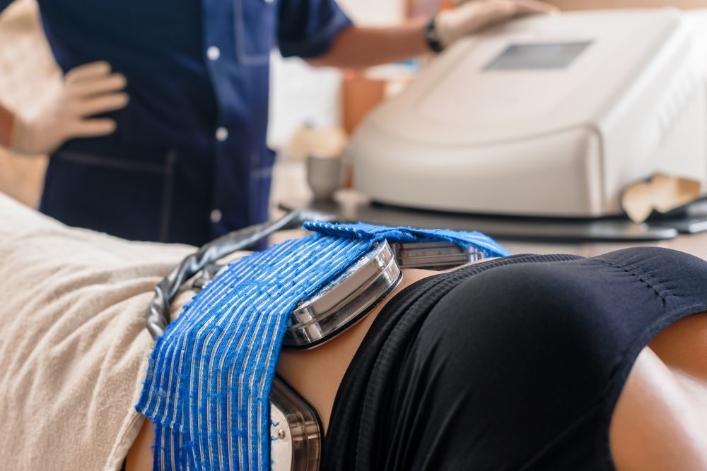 Person undergoing CoolSculpting treatment on their abdomen. Cooling applicators are in place, held by a blue towel.