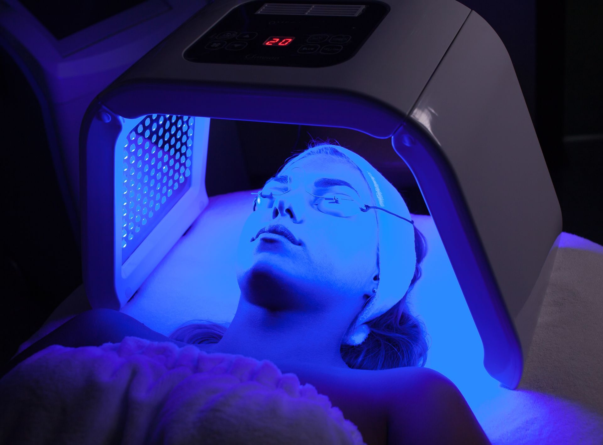 A woman is getting a blue light treatment on her face