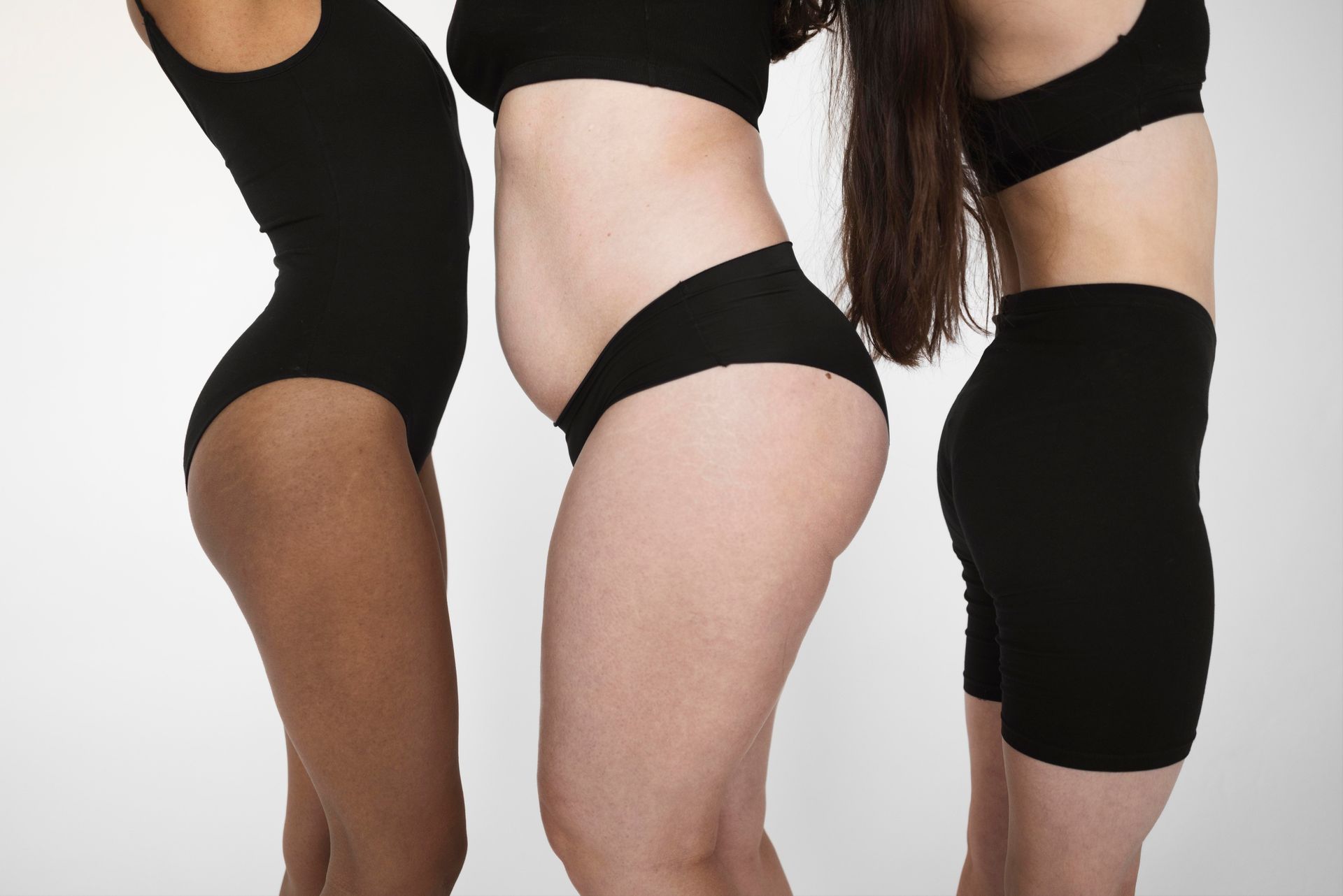 Three women in black underwear are standing next to each other.