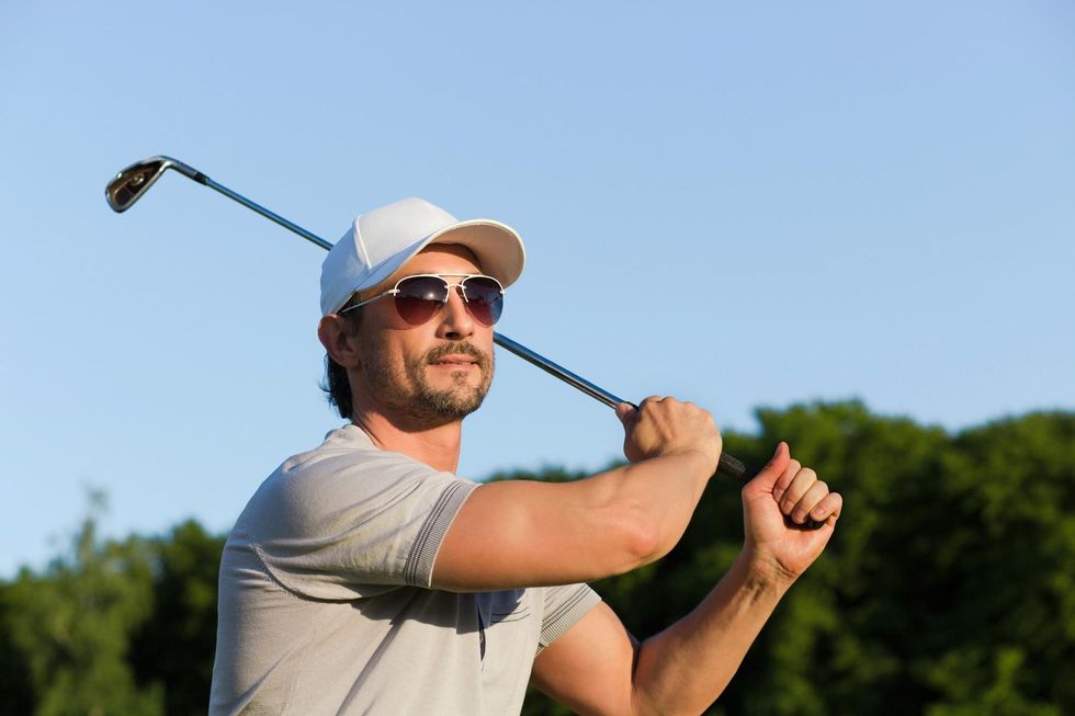 A man is swinging a golf club on a golf course.