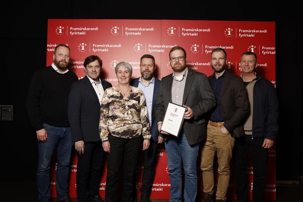 Hópur fólks situr fyrir á mynd fyrir framan rauðan vegg.