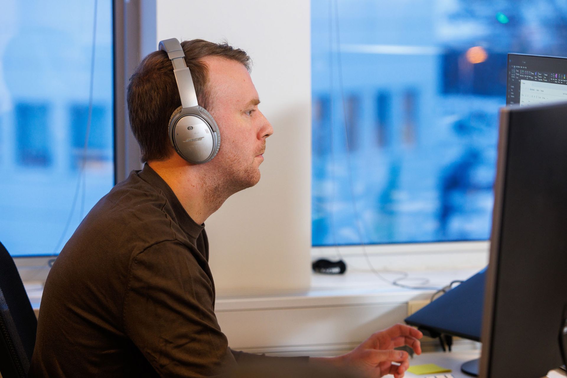 Maður með heyrnartól situr fyrir framan tölvu.