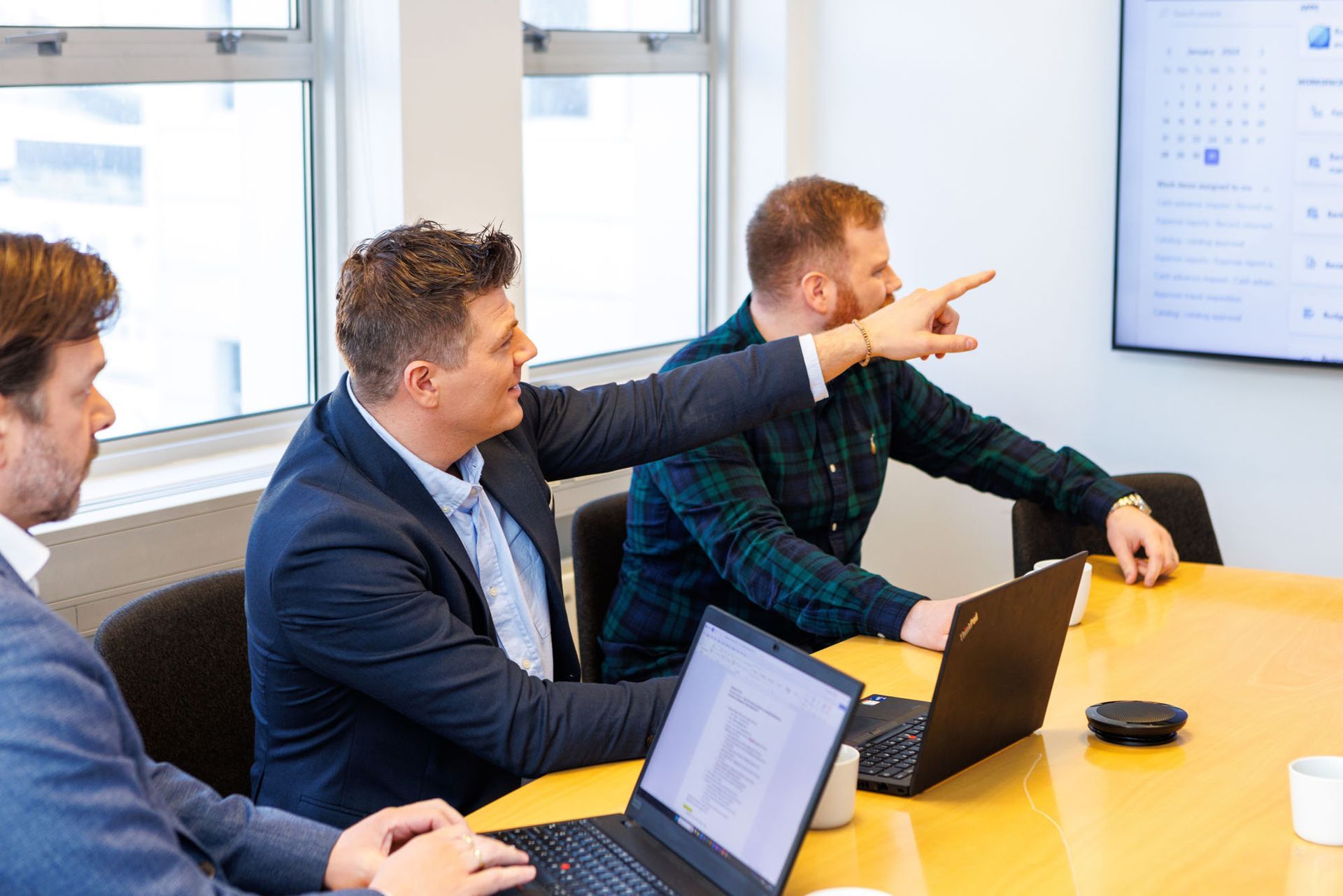 Hópur karlmanna situr í kringum borð með fartölvur.