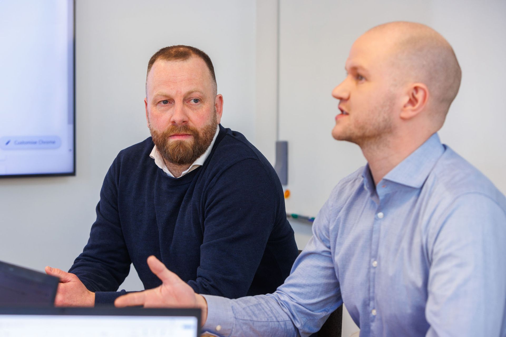 Tveir menn sitja við borð og tala saman.