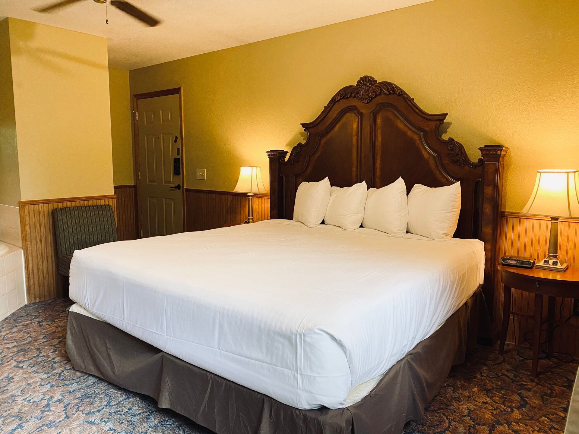 A hotel room with a king size bed and a ceiling fan.