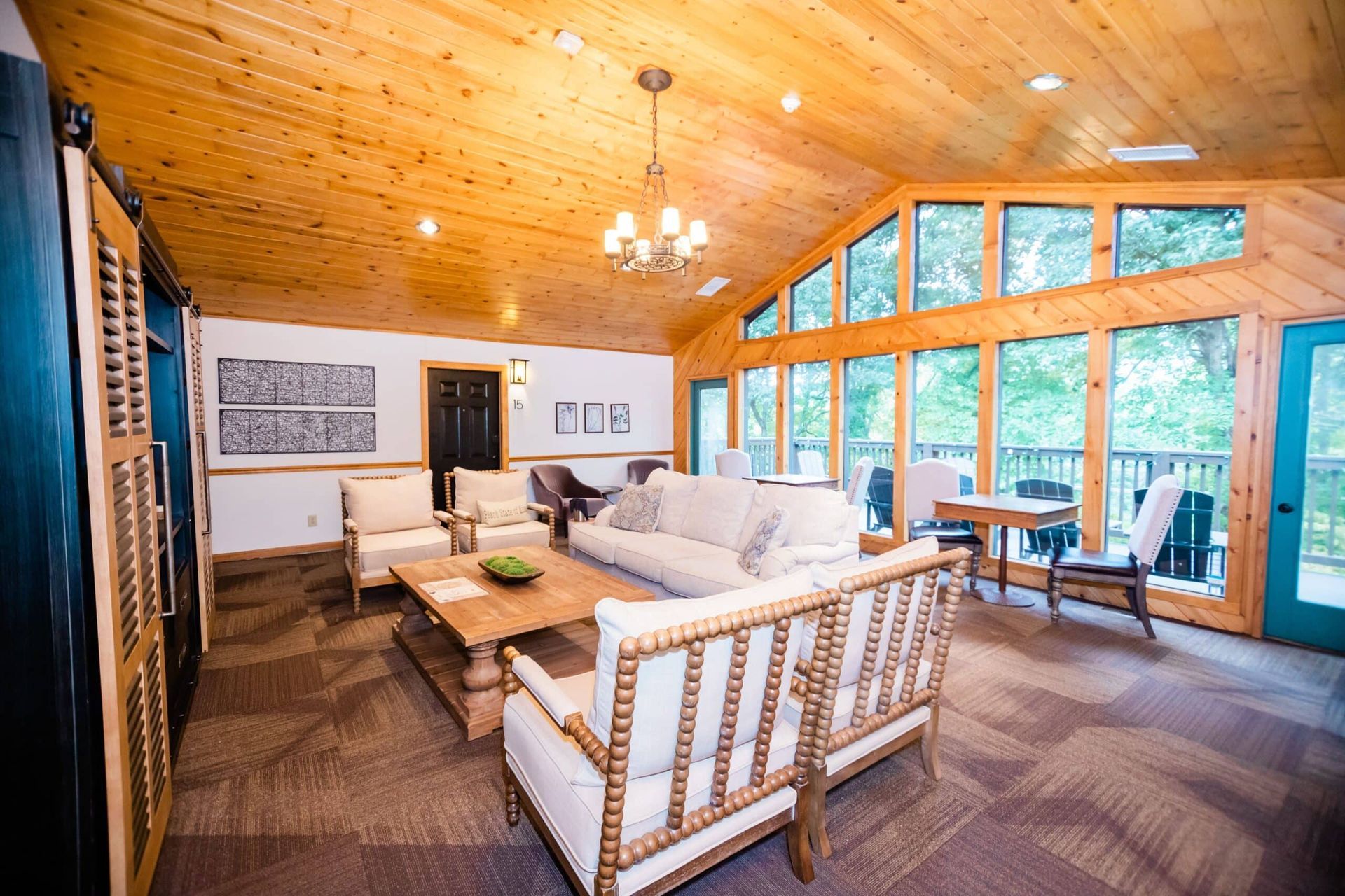 A living room with a couch , chairs , table and lots of windows.