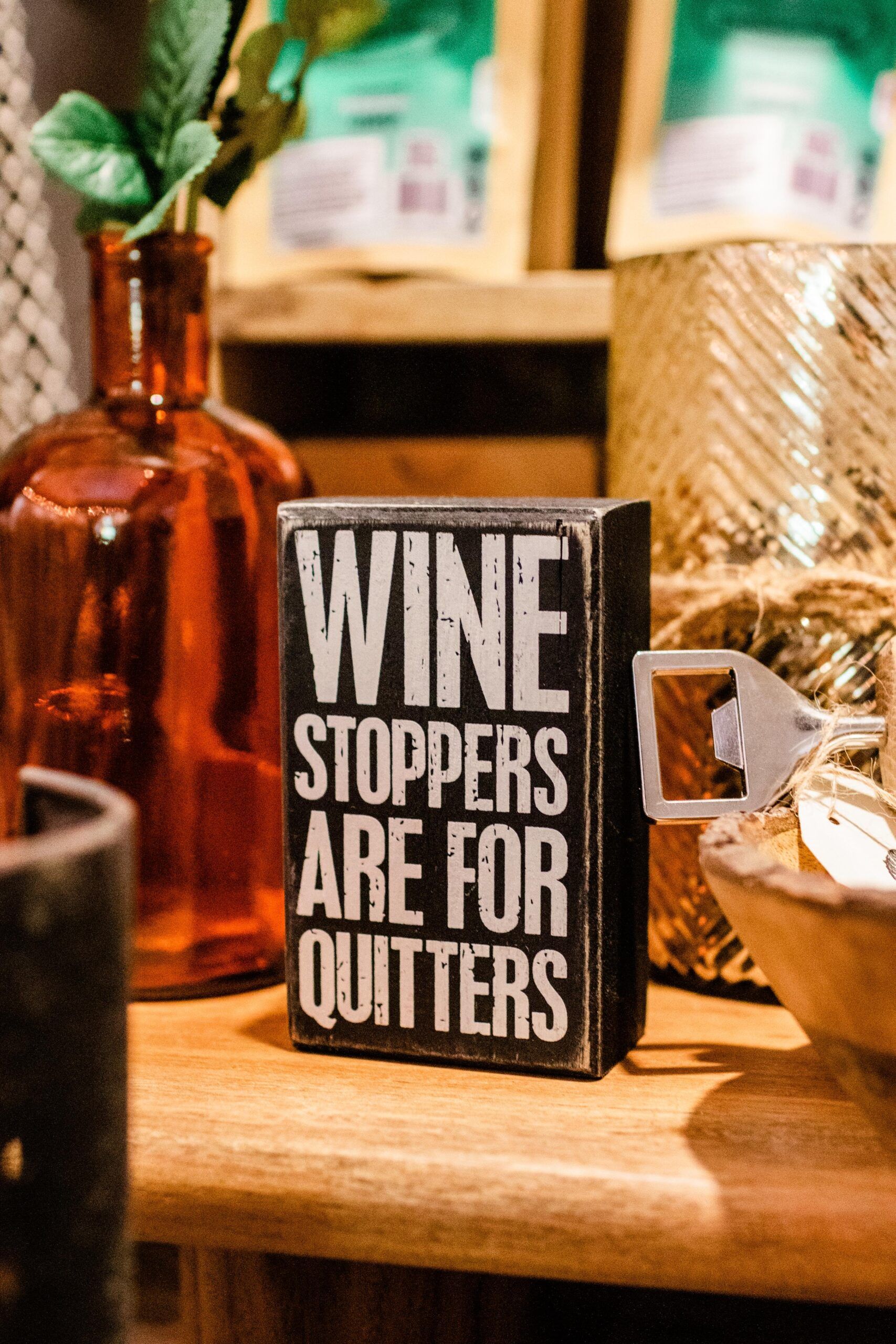 A wooden sign that says `` wine stoppers are for quitters '' is sitting on a wooden table.