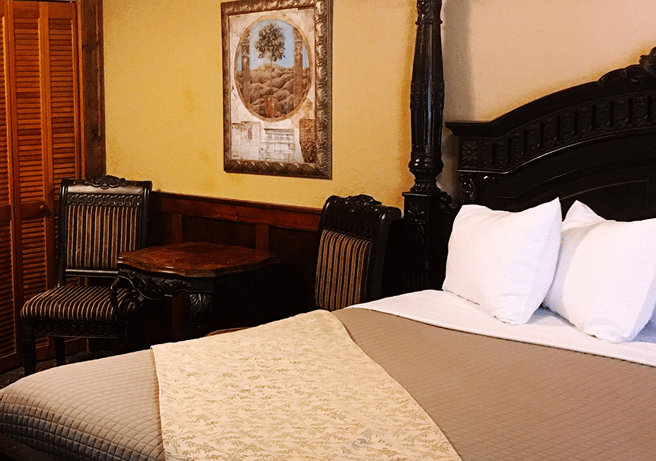 A hotel room with a four poster bed and a table