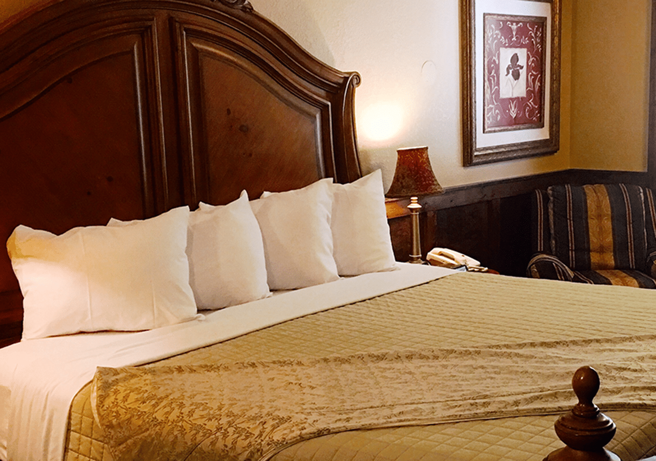 A hotel room with a large bed and a lamp
