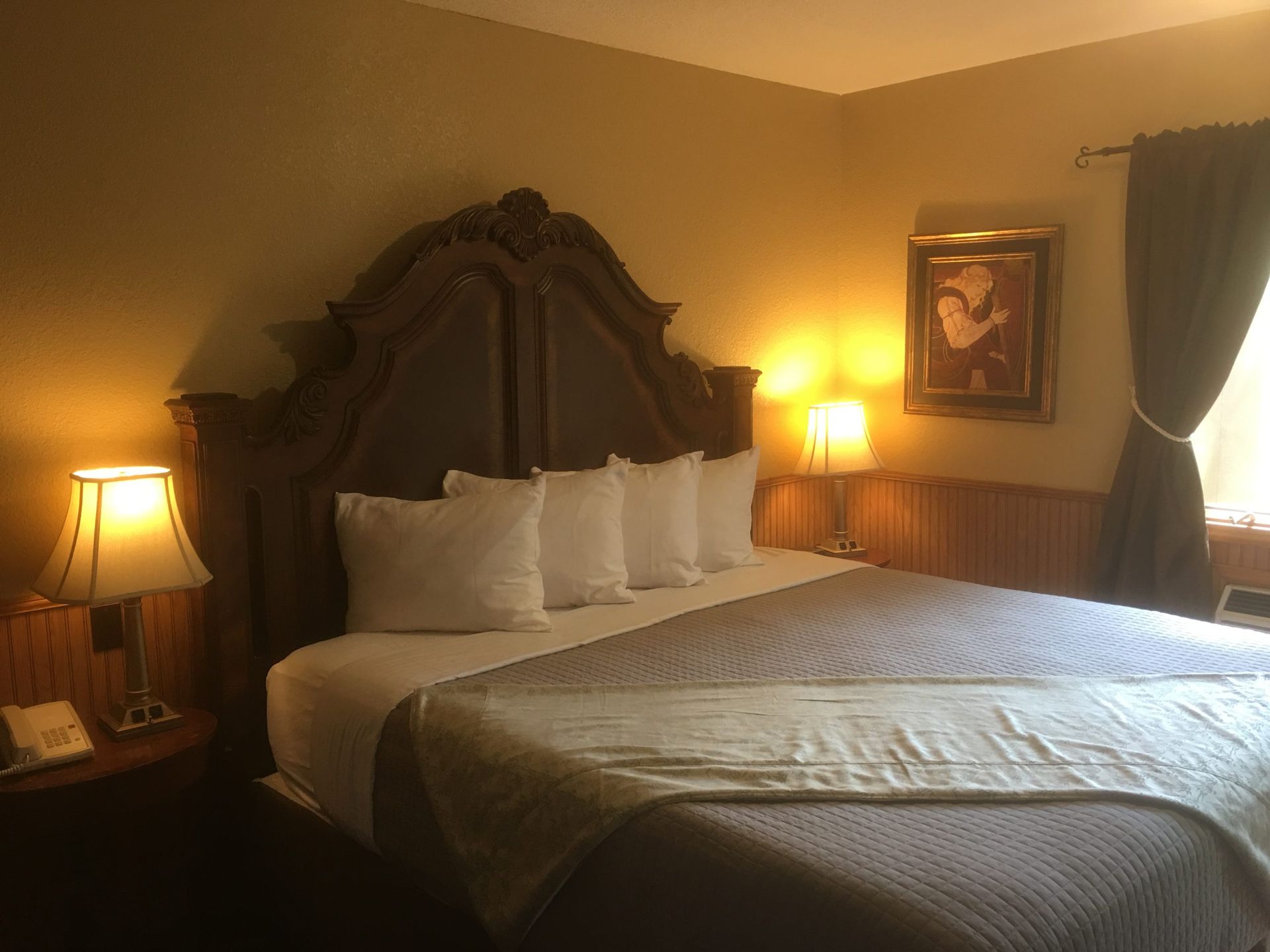 A hotel room with a large bed and two lamps