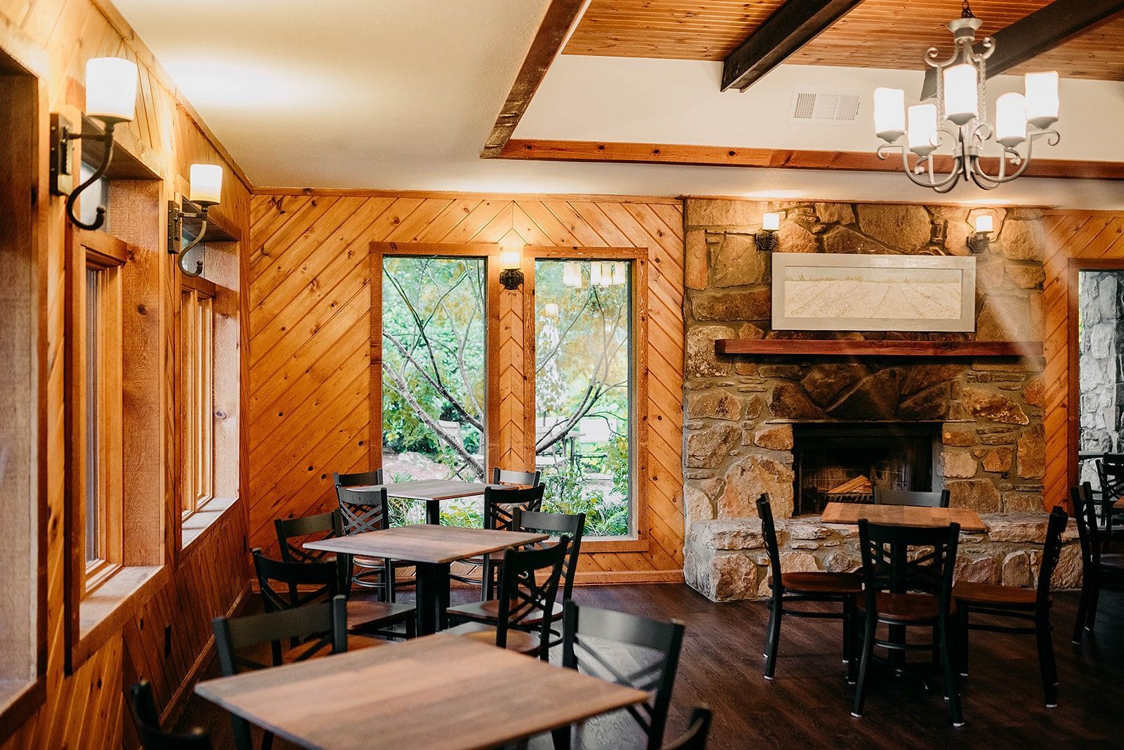 A dining room with tables and chairs and a fireplace.