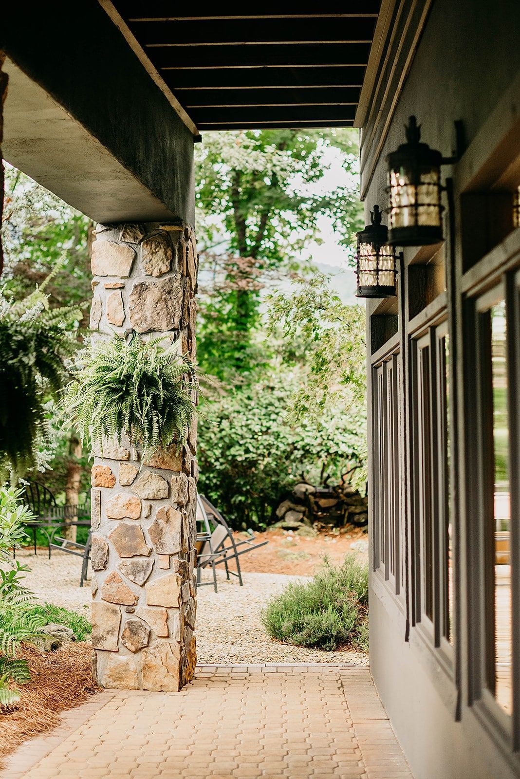 A porch with a stone pillar and lanterns on the side of a house.