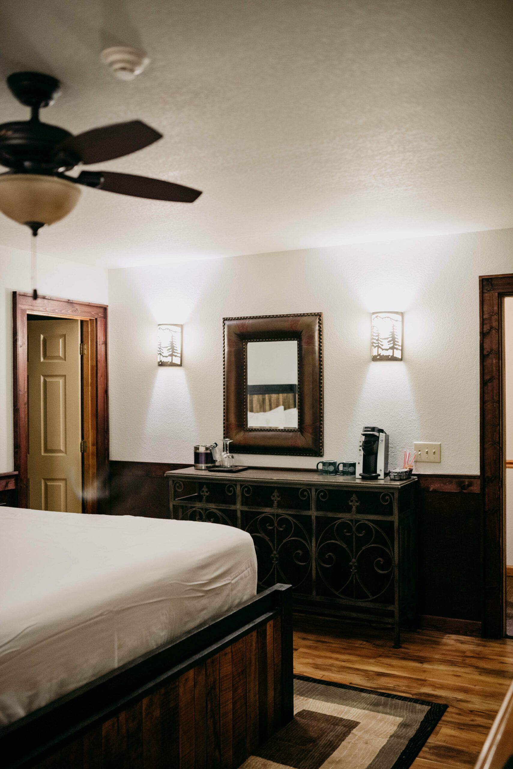 A bedroom with a bed , dresser , mirror and ceiling fan.