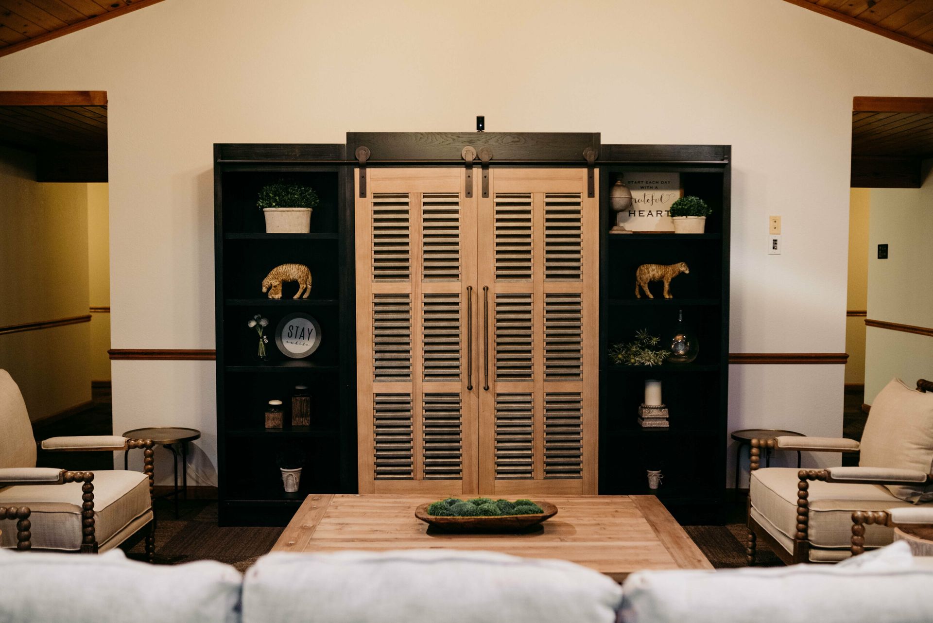 A living room with a couch , chairs , and a sliding barn door.