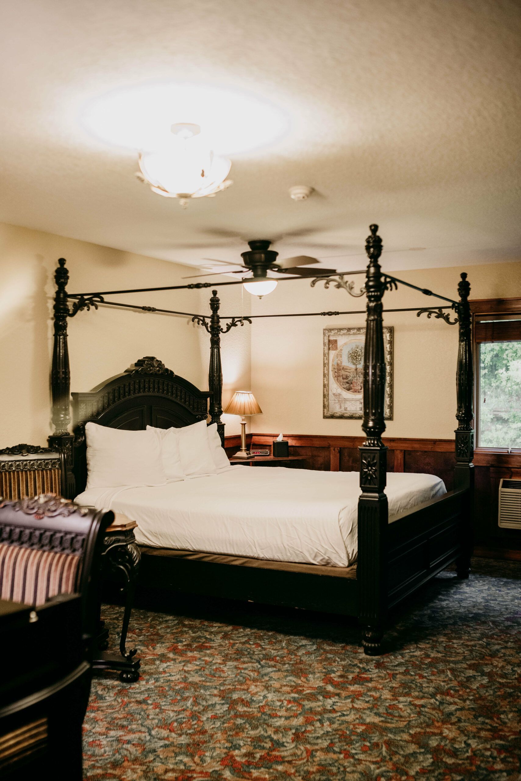 A hotel room with a four poster bed and a ceiling fan.