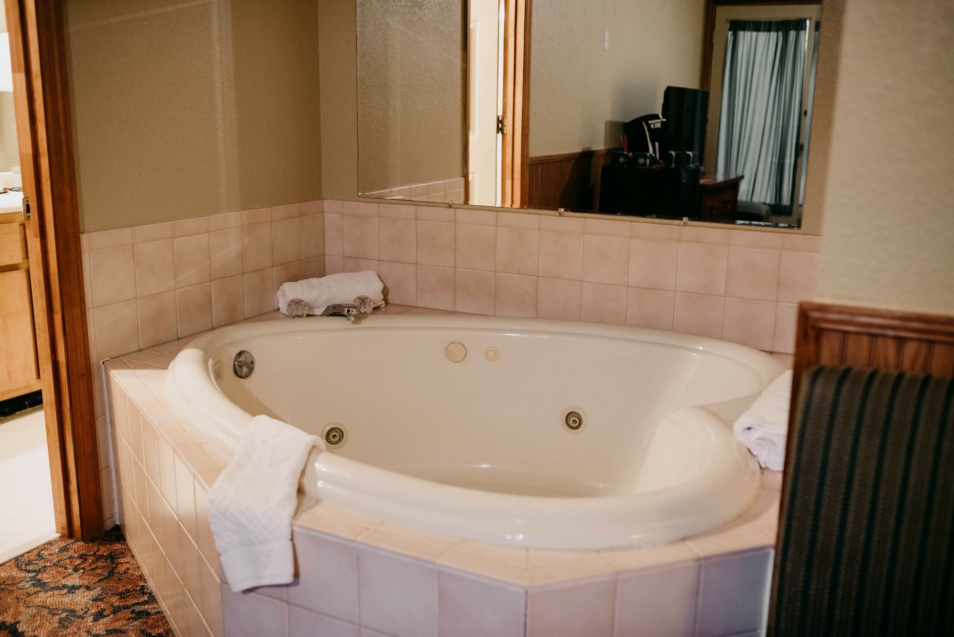 A jacuzzi tub in a bathroom next to a mirror.
