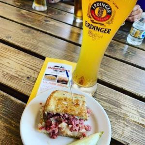 A plate of food and a glass of beer on a wooden table.