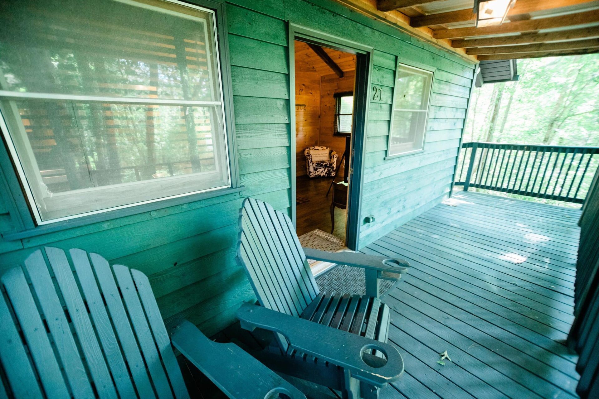 There are two chairs on the porch of a cabin.