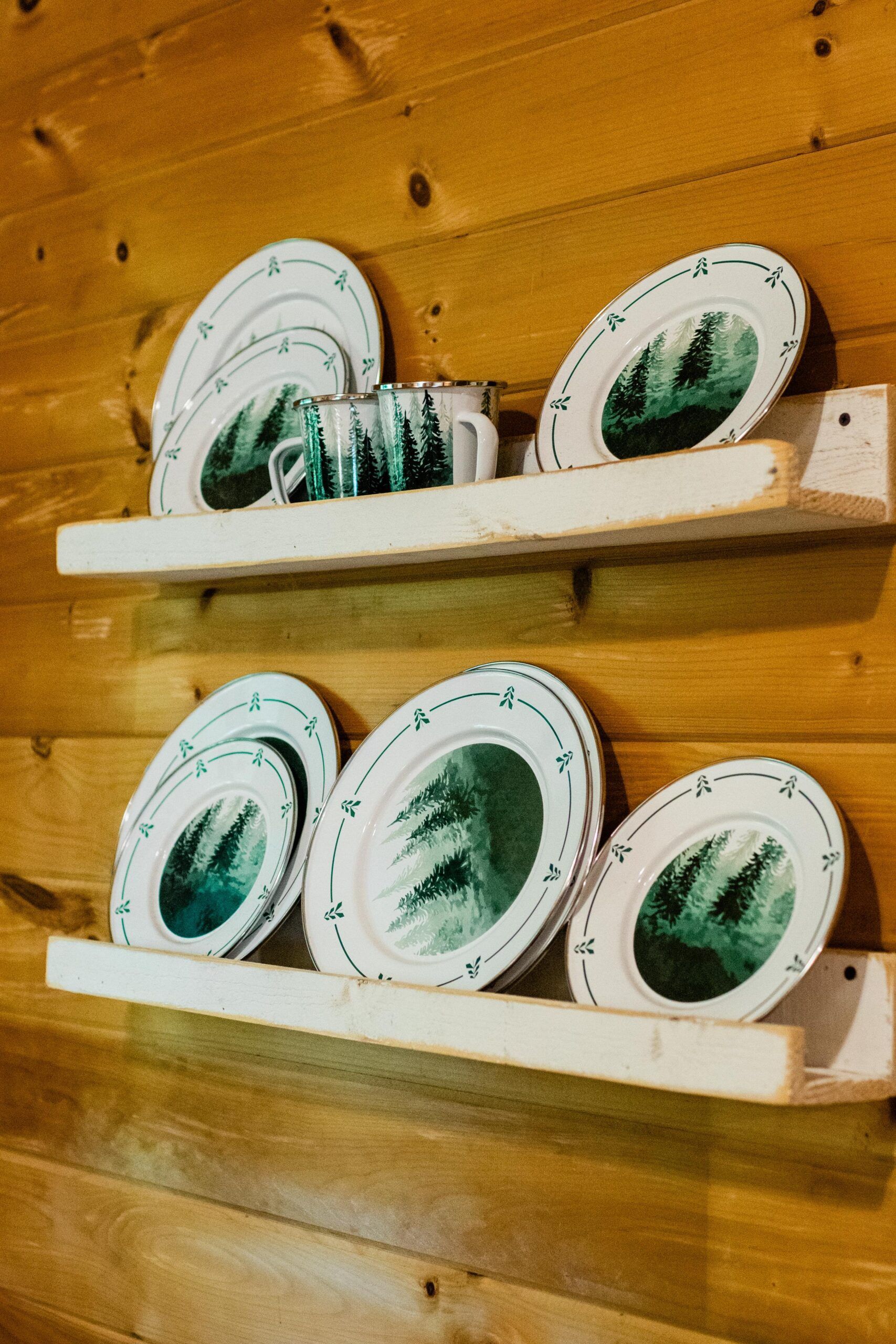 Two shelves filled with plates and mugs on a wooden wall.