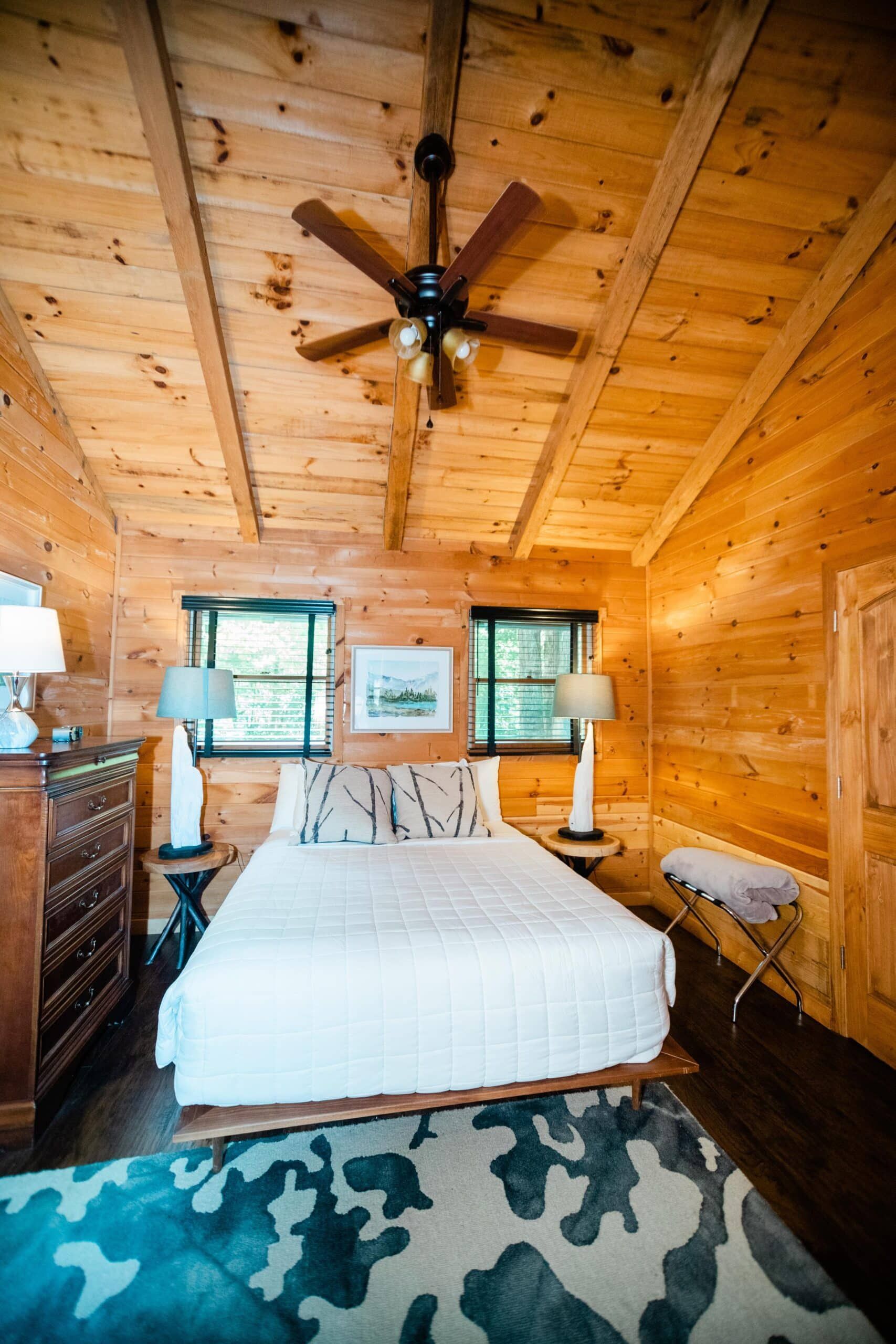 A bedroom in a log cabin with a bed and a ceiling fan.