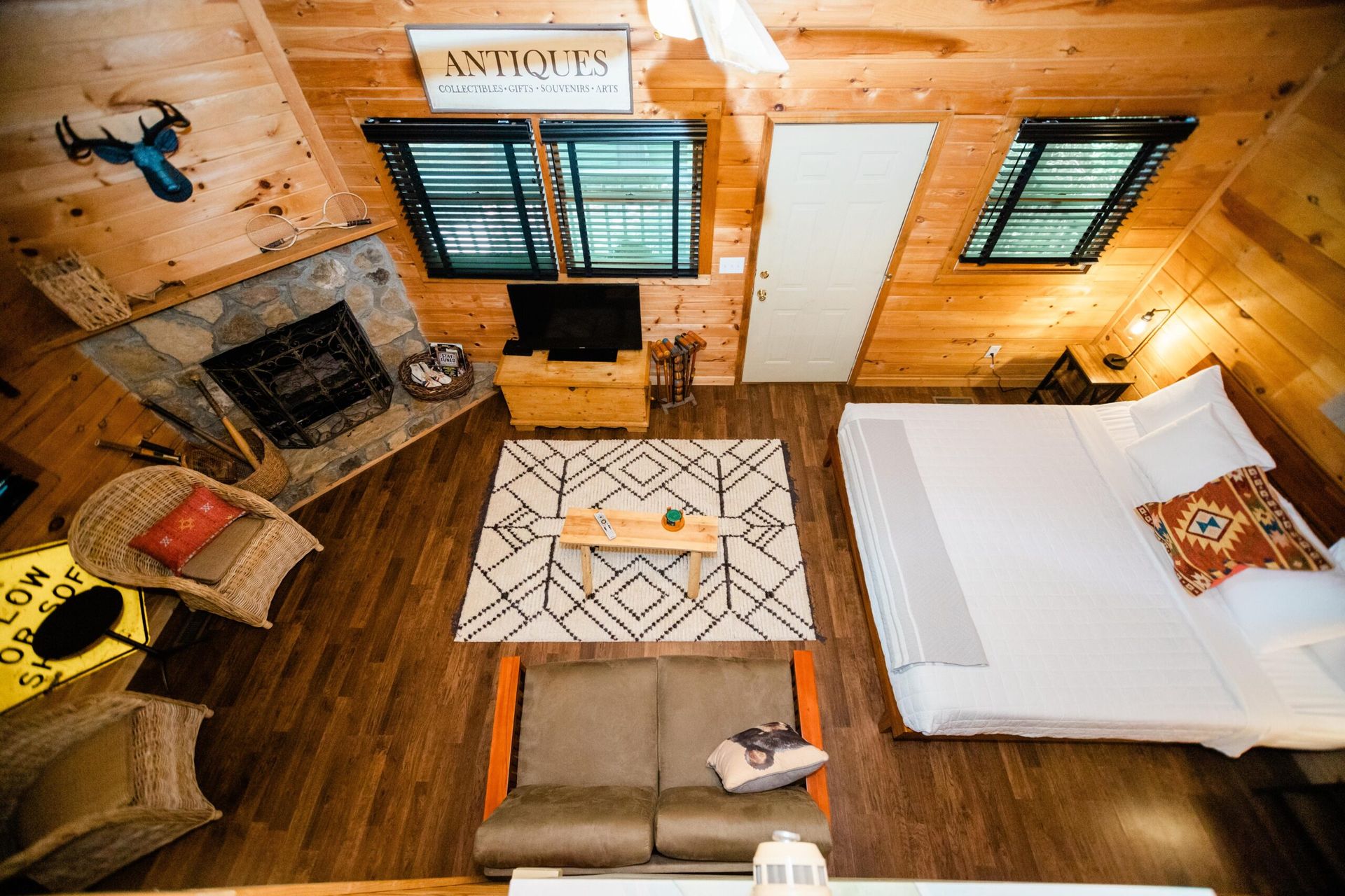 An aerial view of a cabin with a bed , couch , fireplace and television.