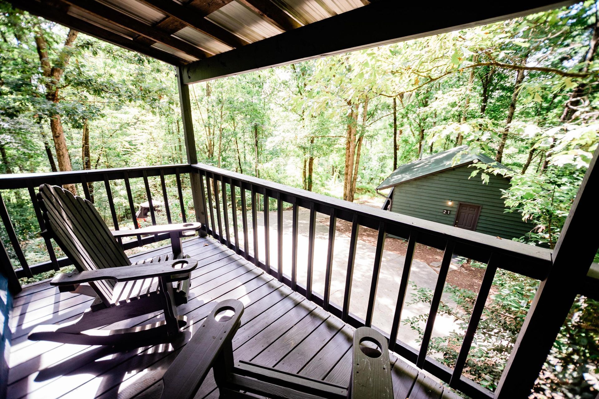 A wooden deck with rocking chairs and a view of the woods.