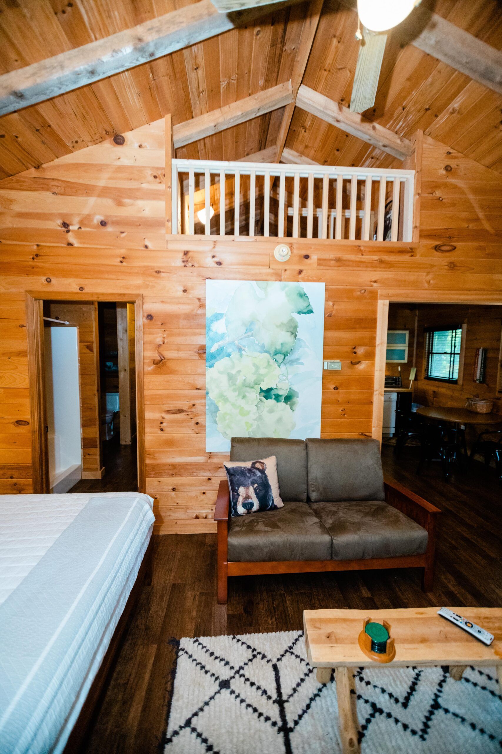 A living room in a log cabin with a couch and a bed.