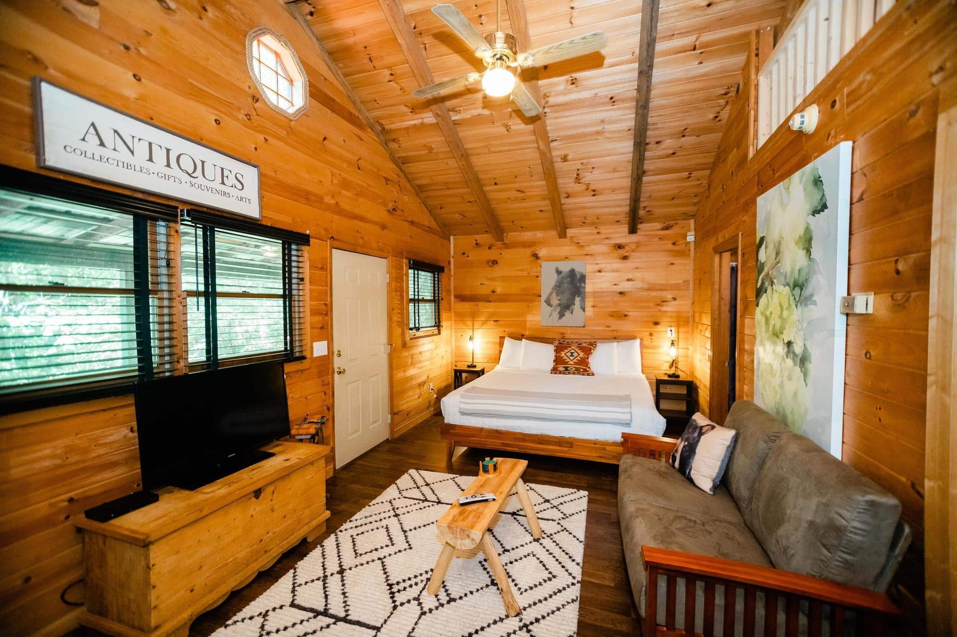 A wooden cabin with a bed , couch , and television.